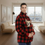 Men wearing a Red and Black Plaid sweatshirt with a dog inside the pouch in a living room