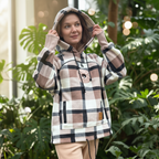 Woman wearing a Beige Plaid hoodie with plants in the background