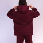 Person wearing a  Burgundy hoodie and pants against a white background