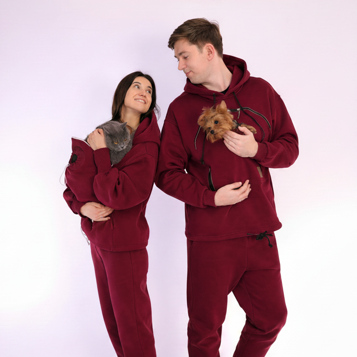 Two people wearing matching  Burgundy sets holding small dog and cat on a white background Основне зображення