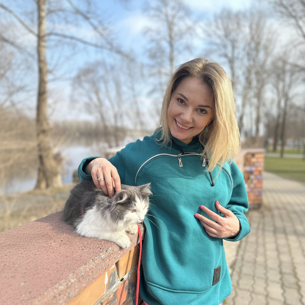 Woman in teal jacket with a cat on a bench outdoors