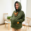 Women wearing a khaki sherpa hoodie with a pocket featuring a small dog, standing in a room with furniture and decor.