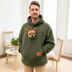 Men wearing a green Khaki hoodie with a dog pocket, standing in a room with light-colored walls and wooden furniture.