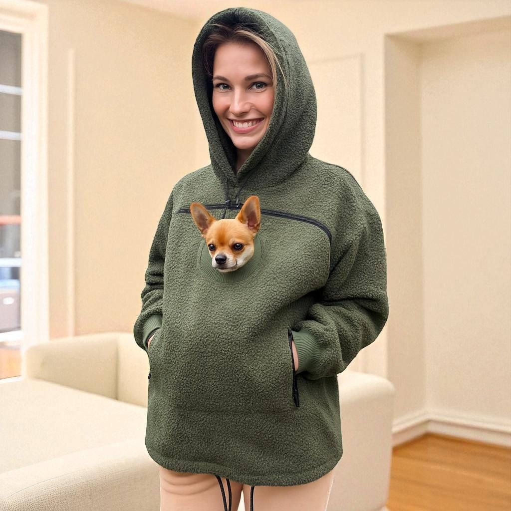 Person wearing a Khaki Sherpa hoodie with a dog peeking out of the front pocket, standing in a room.