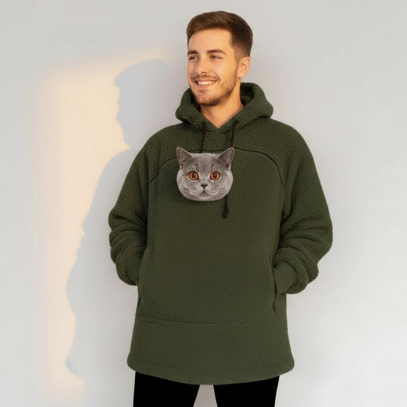 Man wearing a green khaki color hoodie with a cat face design against a plain background