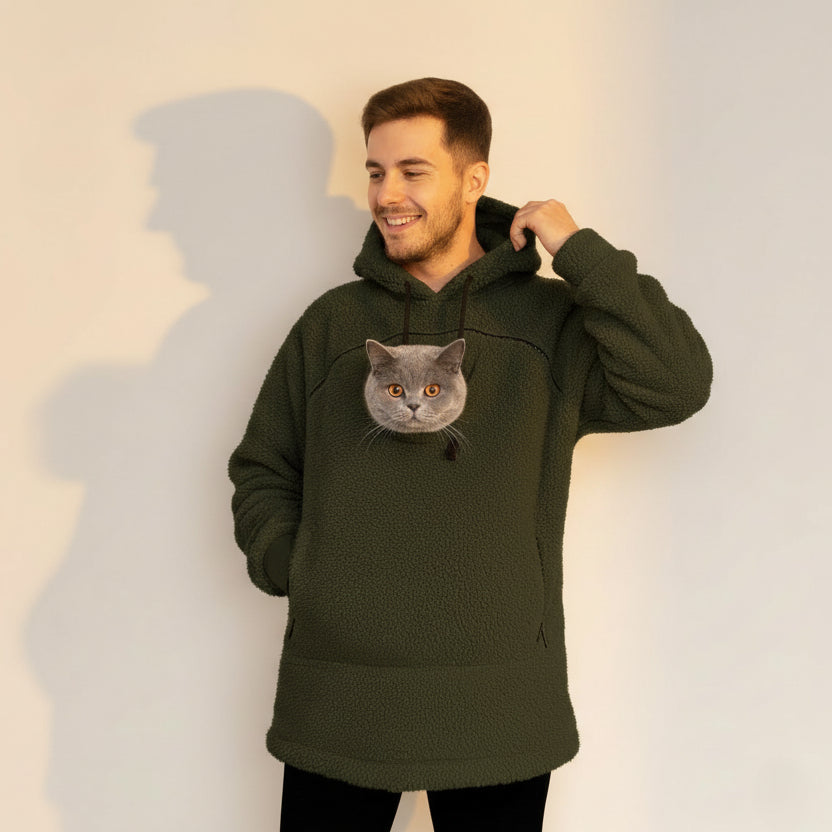 Man wearing a green khaki color hoodie with a cat face design against a plain background