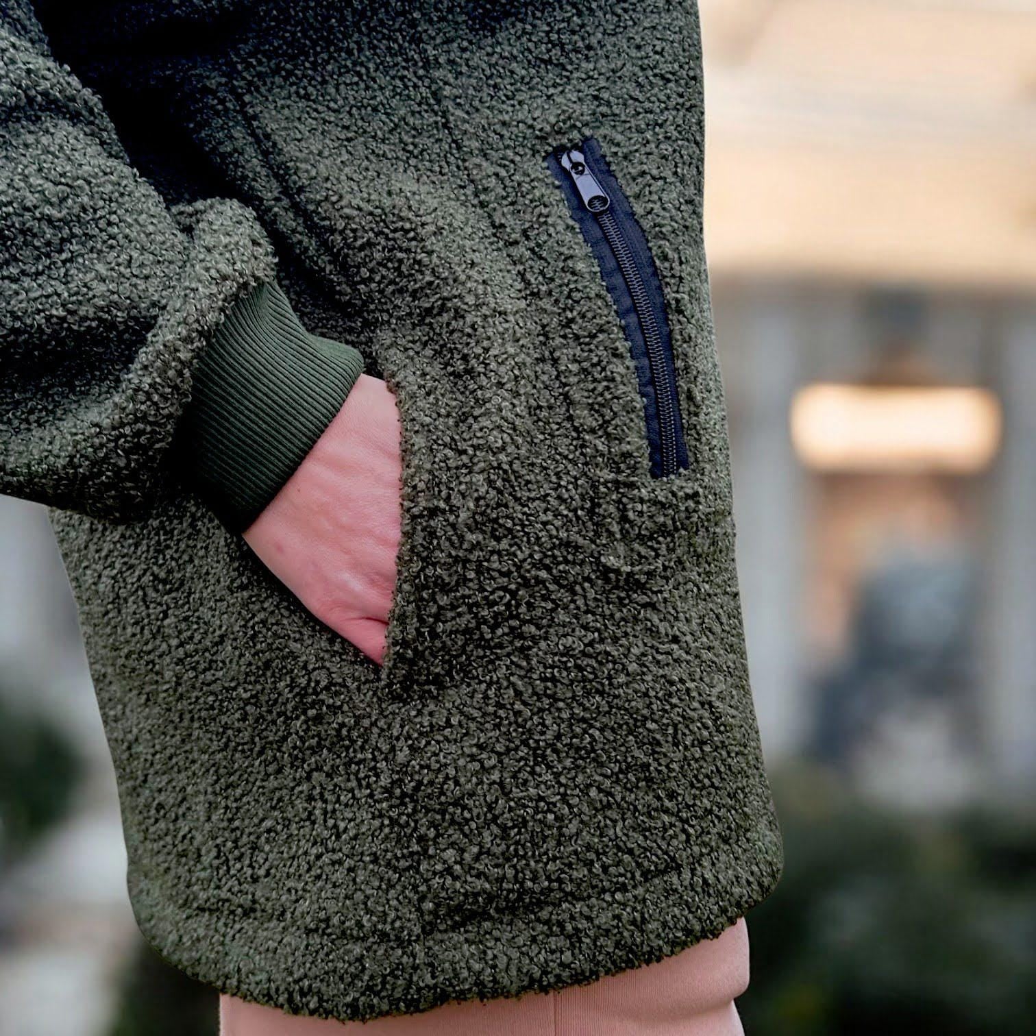 Person wearing a Khaki Sherpa fleece jacket with a blurred background