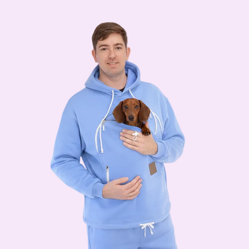 Man wearing a Light Blue hoodie holding a small dog on a white background