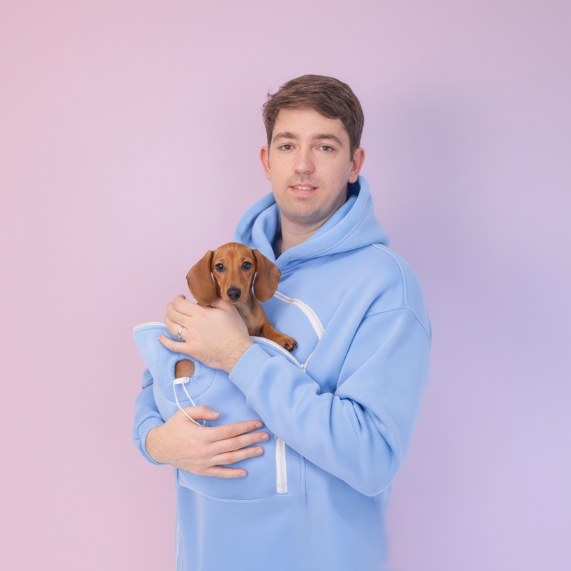 Man in a Light Blue hoodie holding a small brown dog against a light purple background Main image