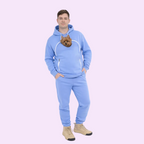 Person wearing a light blue tracksuit with a dog peeking out from the chest pocket against a white background