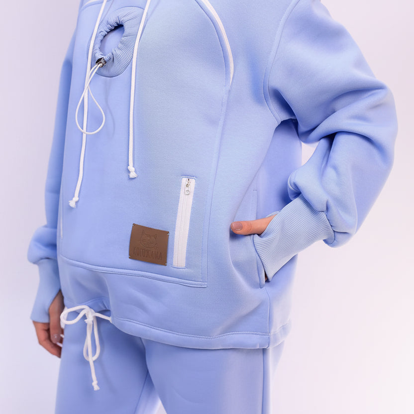 Light blue hoodie with a brown patch and white zipper on a light gray background