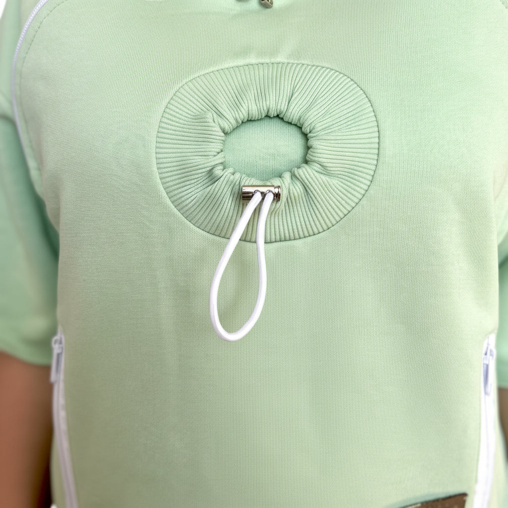 Lime green shirt with a hole design for pet head and white drawstring on a blurred background
