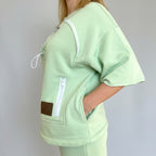 Lime green scrub top worn by a person on a plain background