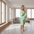 Woman in a lime green outfit holding a cat in a modern living room.