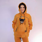 Person wearing an Mustard hoodie with a dog on a white background