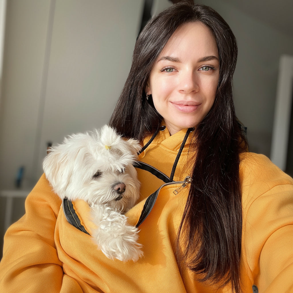 Woman wearing pet carrier hoodie while cuddling small dog