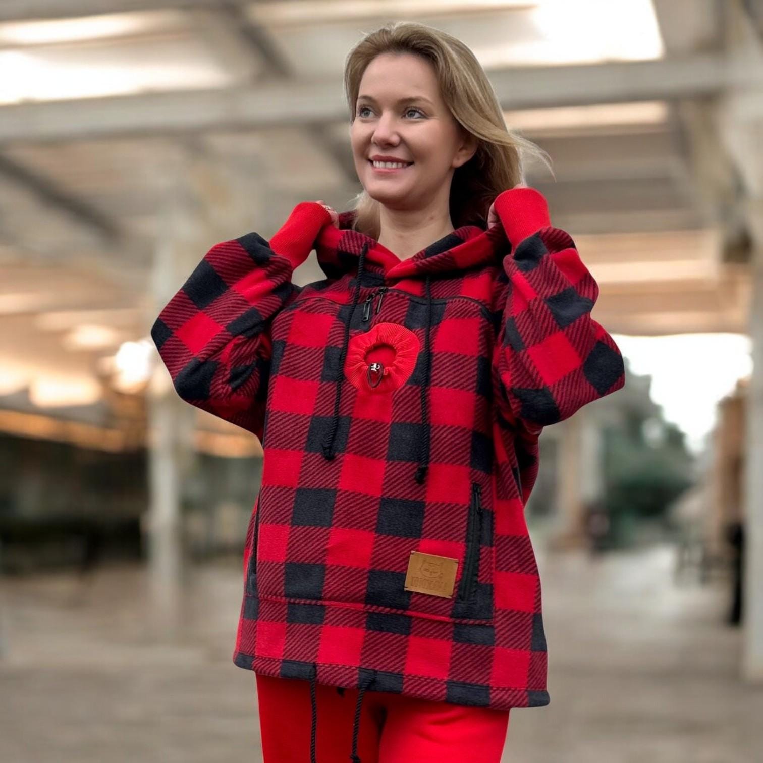 Person wearing a red and black checkered hoodie with a blurred background