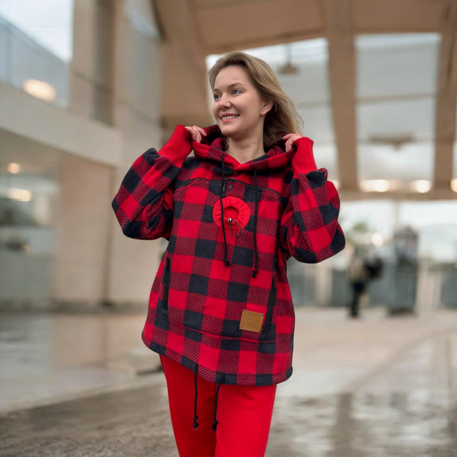 Woman wearing a red and black plaid jacket with a heart design in an indoor setting.