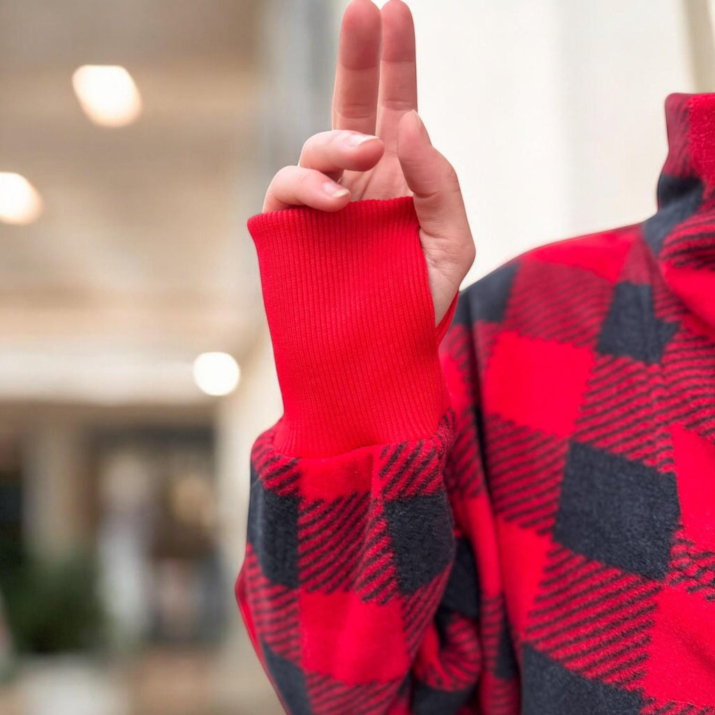 Red and black checkered sweater with a blurred indoor background