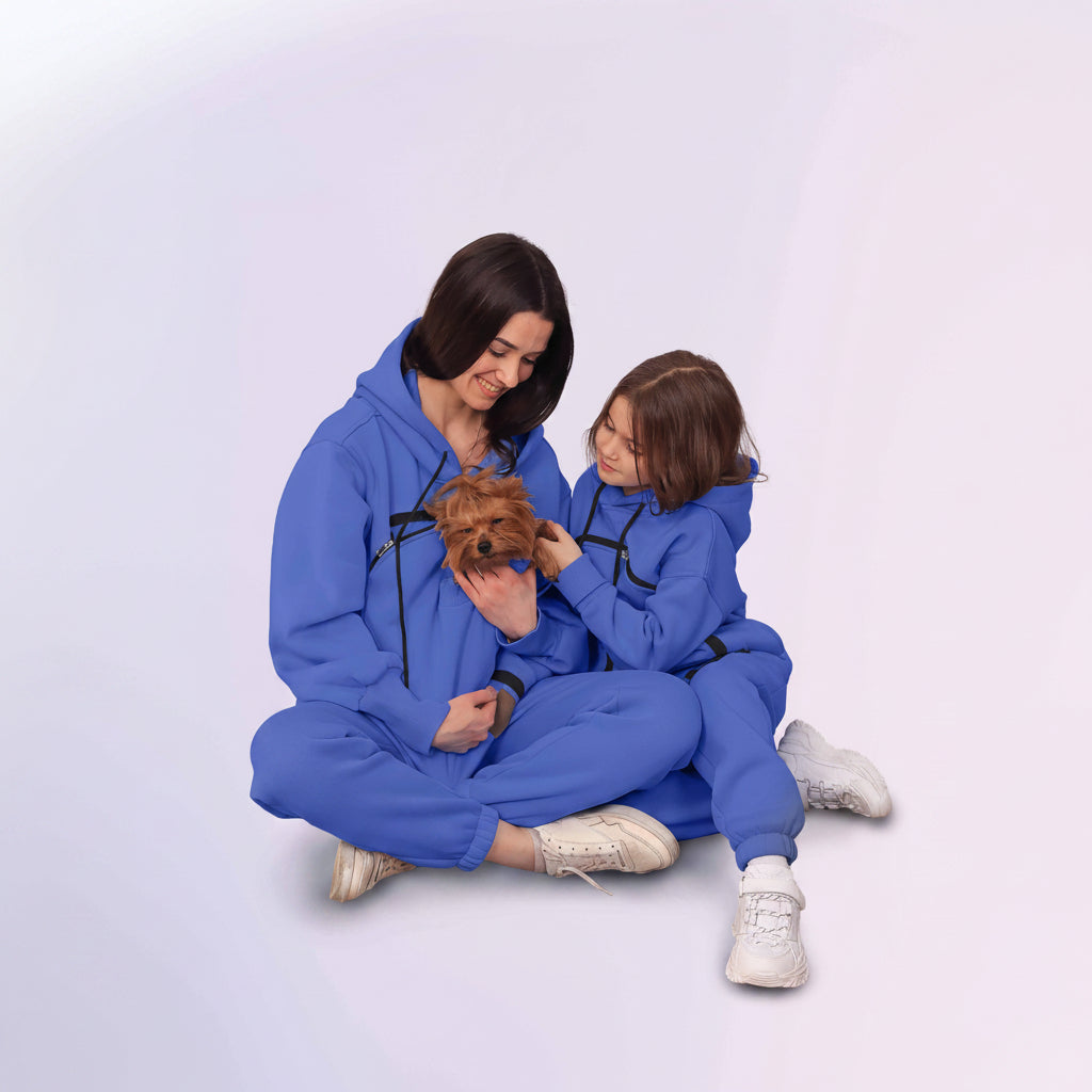Two people in matching Royal Blue outfits sitting on the floor with a small dog.