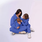 Two people in matching Royal Blue outfits sitting on the floor with a small dog.