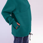 Teal sweatshirt with front pocket on a light purple background