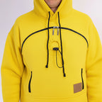Yellow hoodie with black drawstrings and a brown patch on a white background