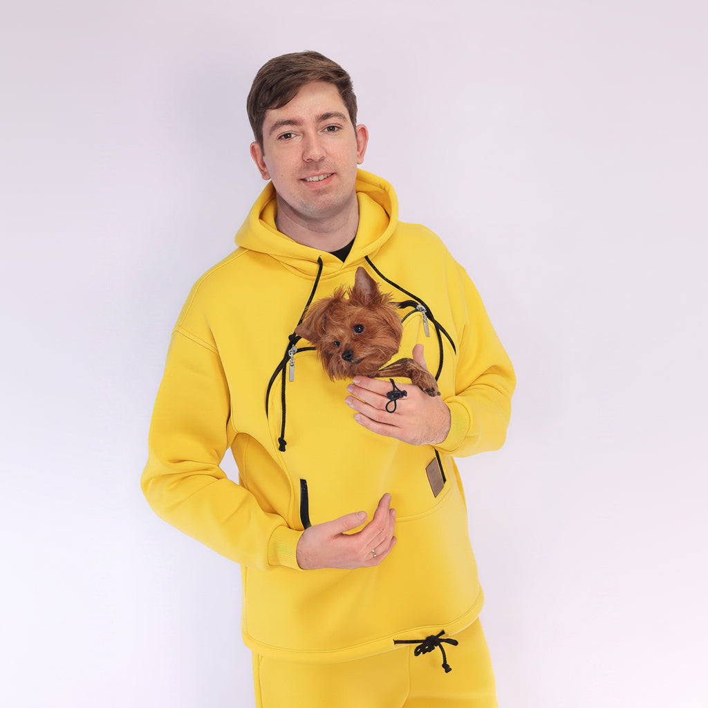 Men wearing a yellow hoodie holding a small dog on a white background