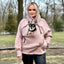Person wearing a beige hoodie with a dog graphic outdoors