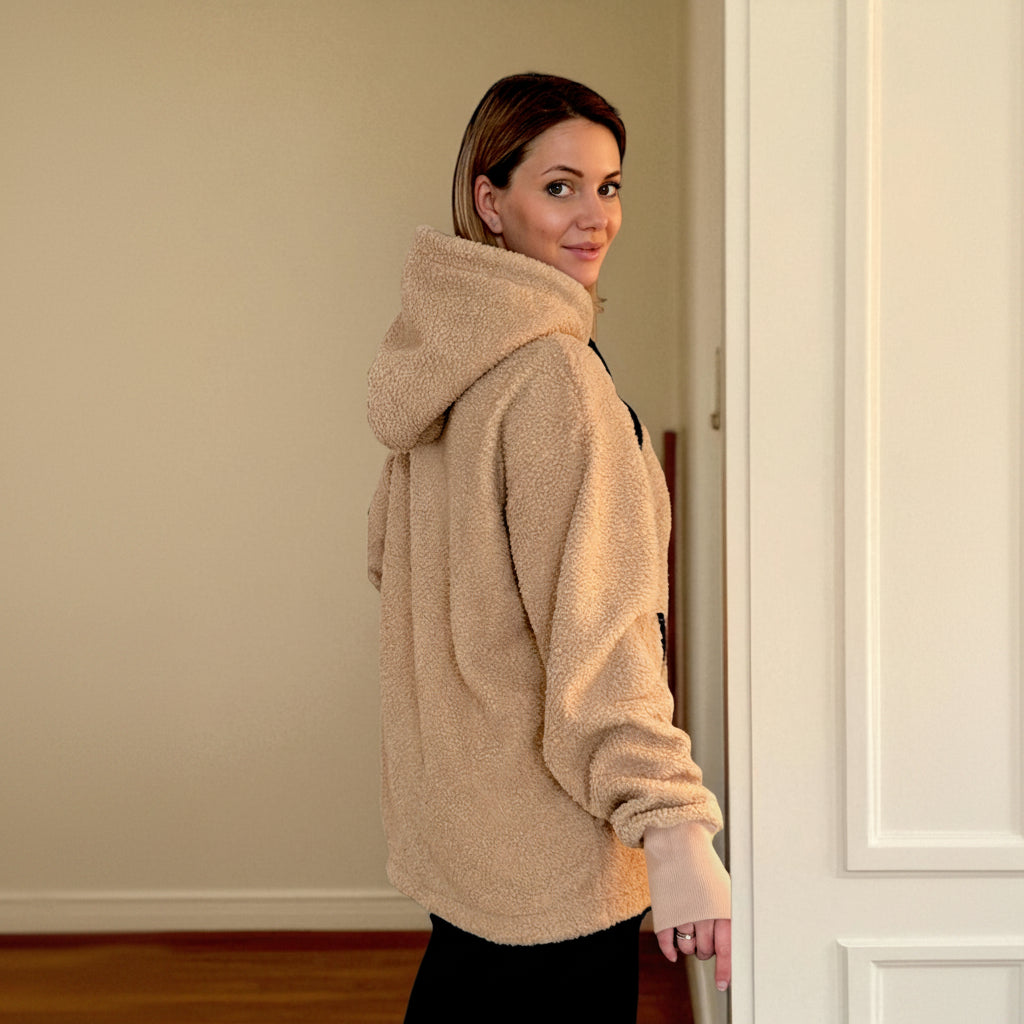 Woman wearing a beige boucle fleece jacket standing in a doorway.