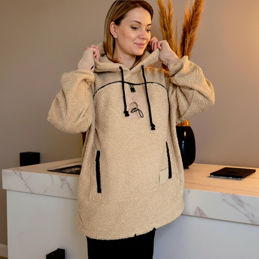 Woman wearing a beige boucle fleece jacket with black accents in an indoor setting.