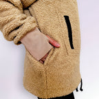 Close-up of a person wearing a beige boucle sherpa jacket with a white background