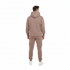 Man wearing a matching brown hoodie and pants set on a white background