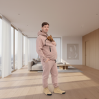 Man wearing a beige tracksuit holding a small dog on a white background