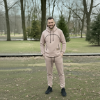 Man wearing a beige hoodie on a cushion outdoors