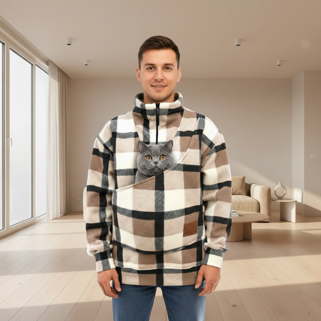 Man wearing a plaid sweatshirt with a cat in a pouch in a living room