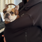 Person wearing a dark hoodie with a small dog peeking out from under it.