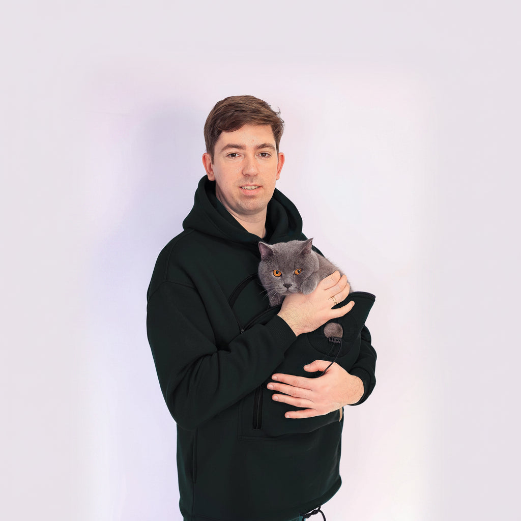 Man holding a gray cat in a black hoodie against a white background