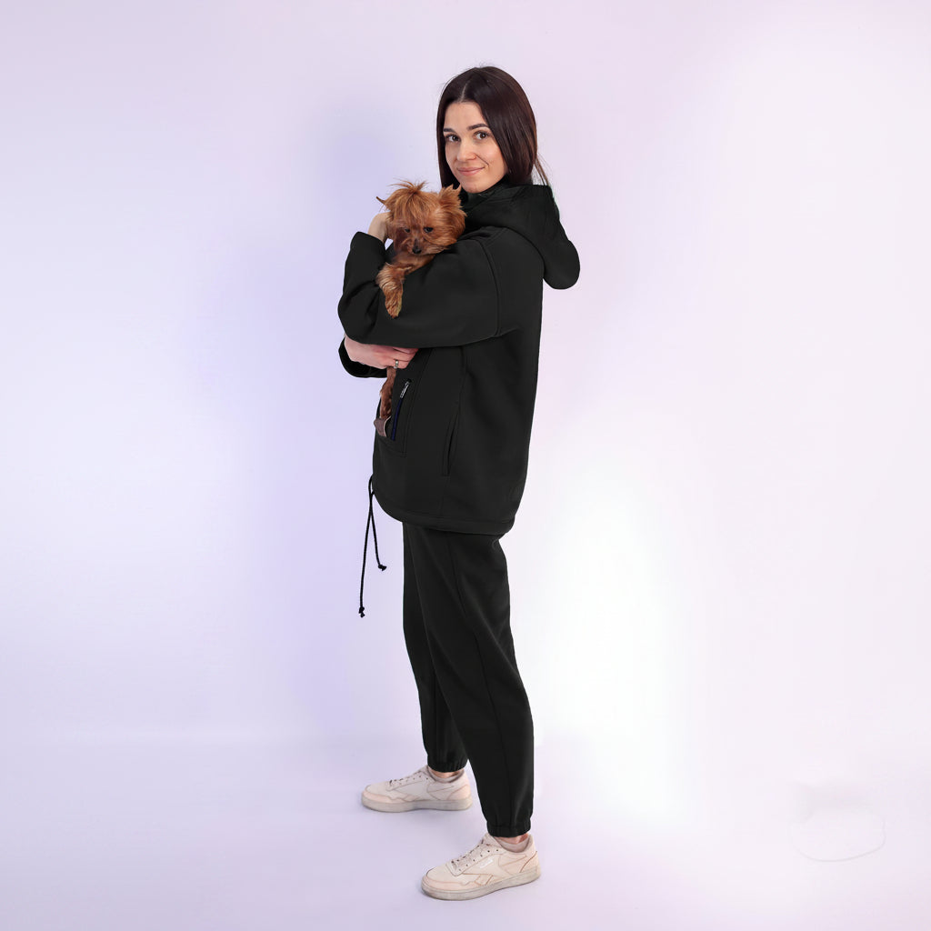 Woman in black tracksuit holding a small dog on a white background