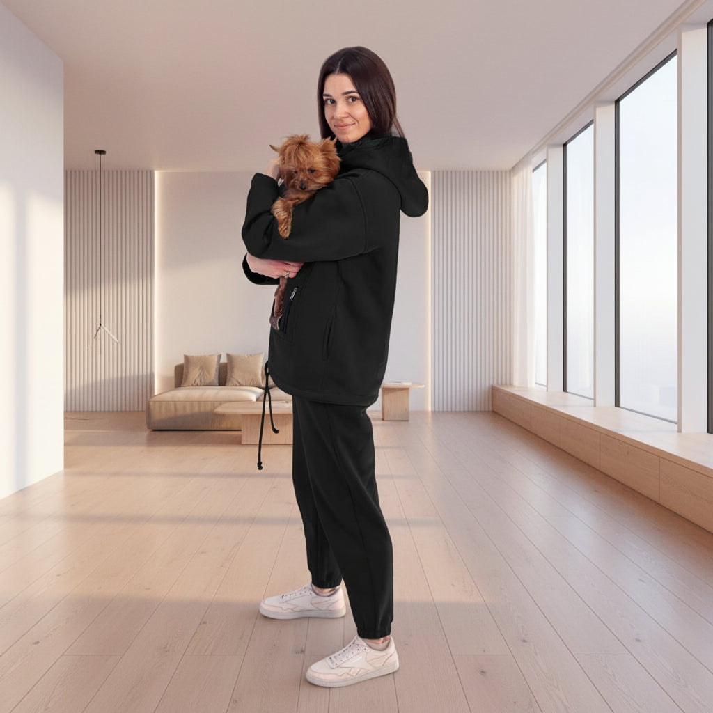 Woman in black tracksuit holding a small dog in a white room with plants. Основне зображення