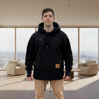 Man wearing a black boucle hoodie with a brown patch standing in a room