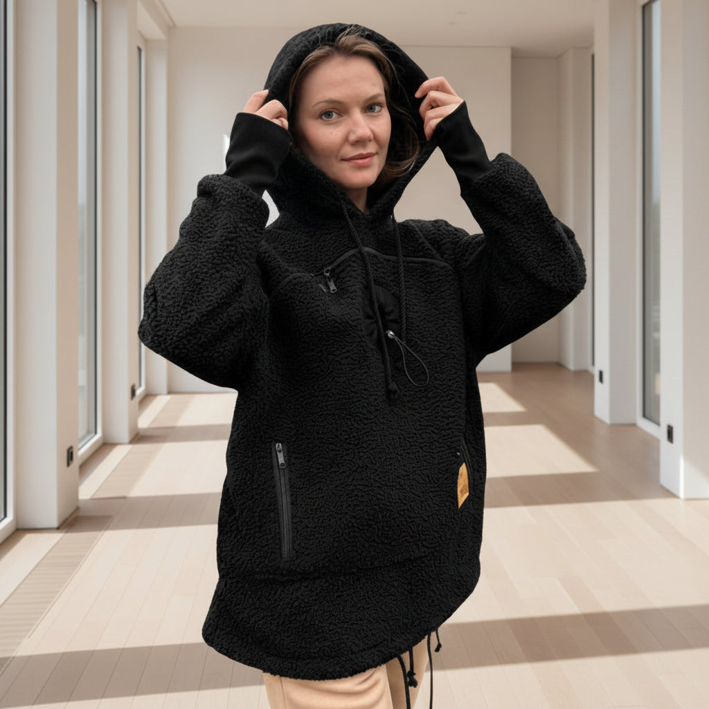 Person wearing a black boucle fleece hoodie in a room with light-colored floor and walls.
