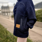 Black boucle fleece hoodie with a brand patch on a blurred outdoor background