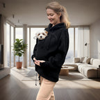 Woman wearing a black boucle hoodie with a cat peeking out