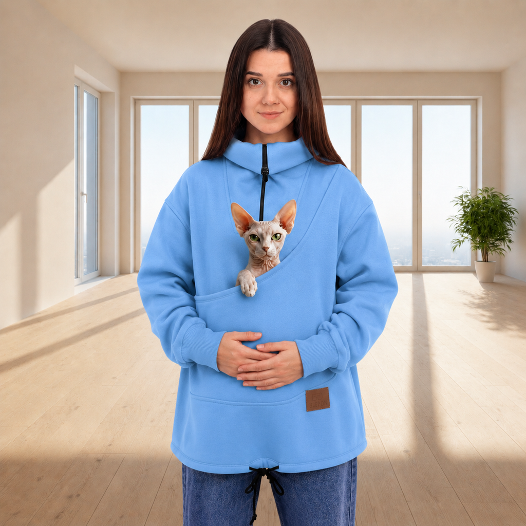 Person wearing a blue sweatshirt with a cat, standing indoors.