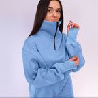 Woman wearing a light blue pullover with a high collar against a white background