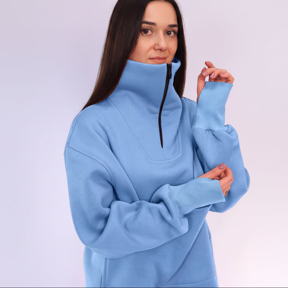 Woman wearing a light blue pullover with a high collar against a white background