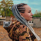 Woman with braided hair holding a gray cat outdoors