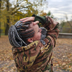 Person wearing a camouflage hoodie with a blurred natural background