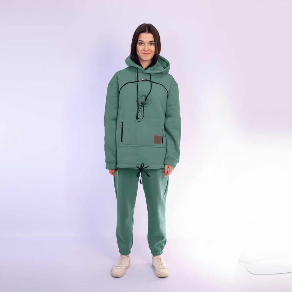 Person wearing a green hoodie and pants set on a white background